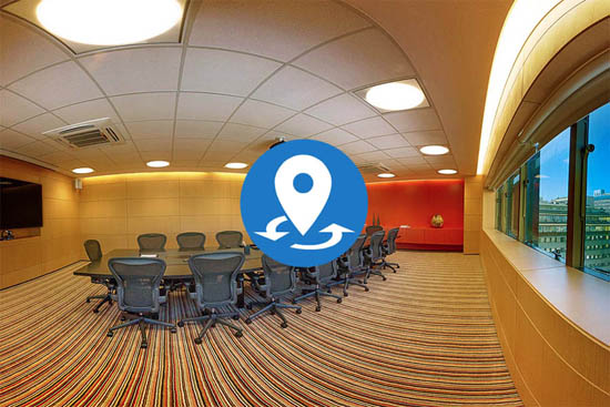 Sala de conferência moderna com grande mesa central, cadeiras ergonômicas, carpete listrado, janela ampla e tela de apresentação.
