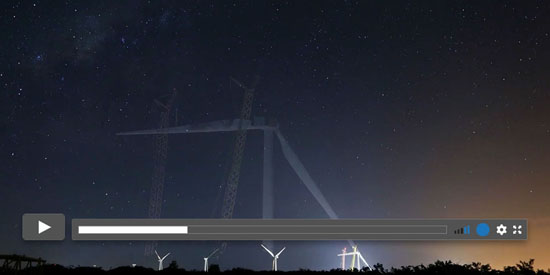 Turbinas eólicas sob um céu estrelado, destacando o avanço da energia renovável e a integração com a natureza noturna. Produção audiovisual.